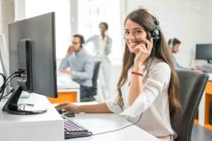 Women taking calls sitting at her computer looking happy