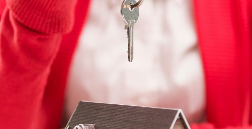Person holding a key above a small model house