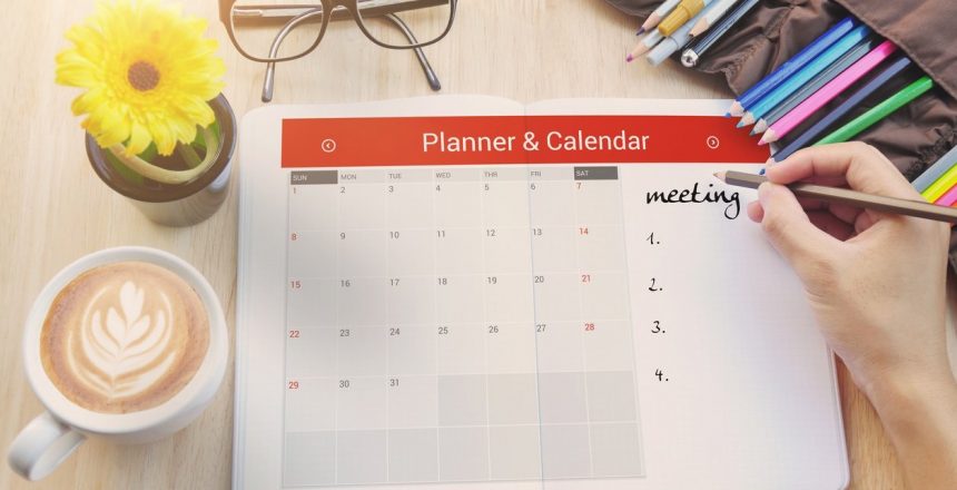 person filling out their calendar with a pencil