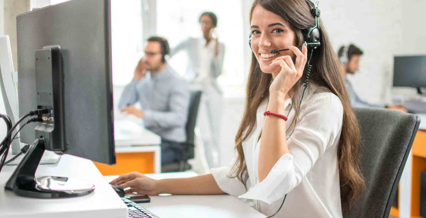 Women taking calls sitting at her computer looking happy